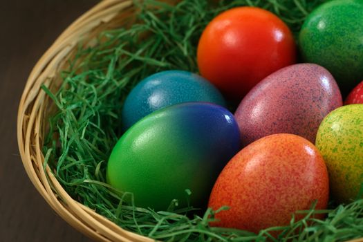 Painted Easter eggs in a basket.  Shallow depth of field focusing on the green egg.
