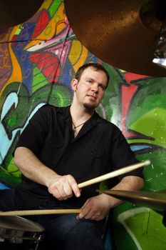 Drummer playing his kit on stage.  Slight movement on the drumsticks.
