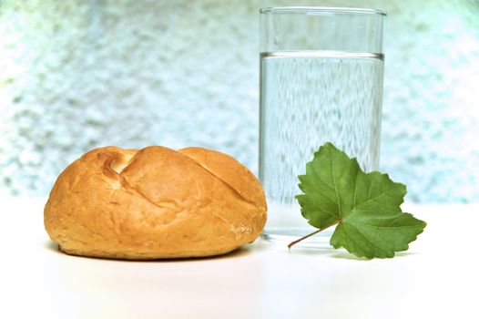 Bread roll and glass of water on kitchen table.