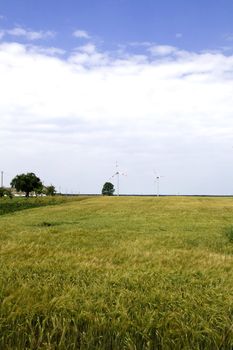 Wind turbine on field against blue sky background