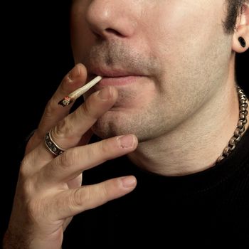 A man smoking a marijuana joint.
