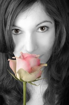 Beautiful young woman smelling a pink rose.  Desaturated version.
