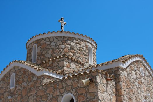 Greek church with cross over blue sky