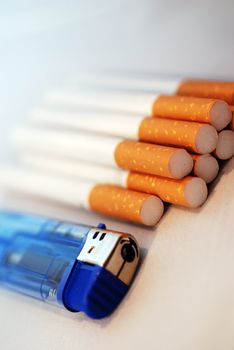 A photograph of a pile of cigarettes and a blue cigarette lighter