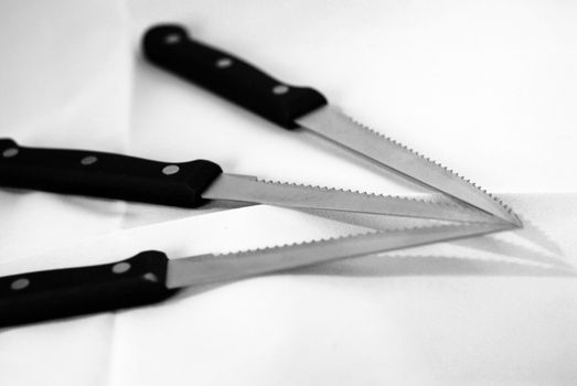A black and white photograph of three knives arranged together