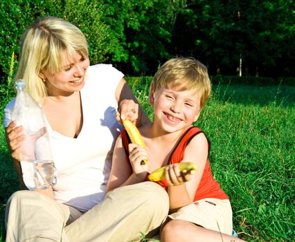 Portrait of the happy beautiful young woman-blonde with the laughing child on picnic. 