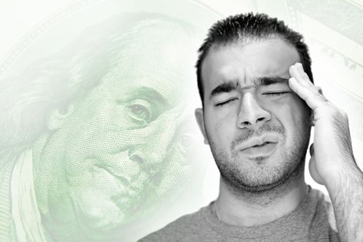 A young man holds his head in anguish as he thinks about his money problems with either debt or unemployment.