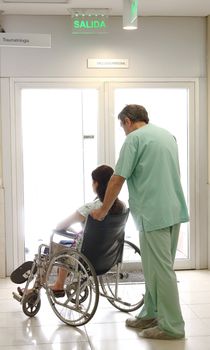 Nurse and a patient using a wheelchair at a hospital hall