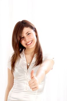 Young, positive woman shows her smiling thumbs-up. She wears bright clothes against a white background with space for text