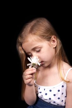 Young girl smelling a flower against black background