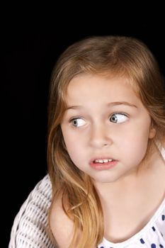 Young girl looking away uncertainly isolated on black