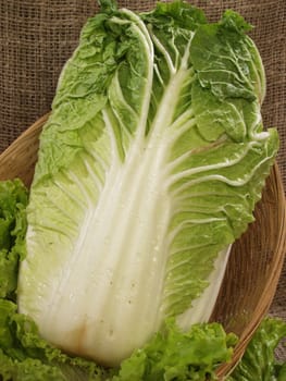 Chinese cabbage with leaves of salad in a basket on a sacking