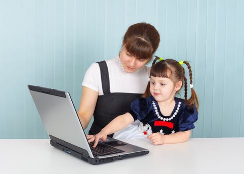 Mother and daughter sitting at table with a laptop