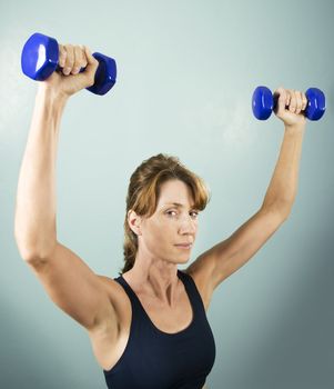 Pretty athletic woman working out with dumbbells