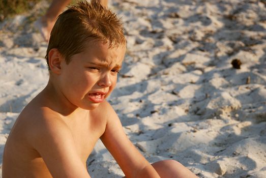 a boy is crying while sitting in a sand