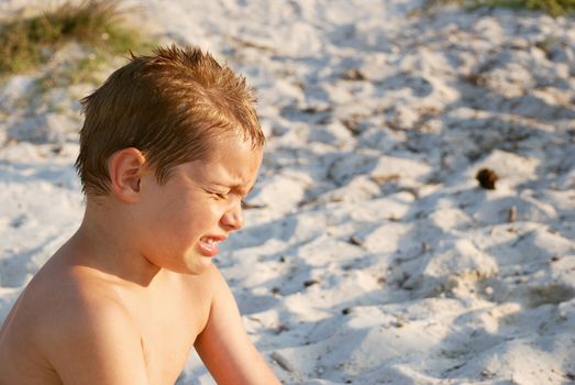 a boy is crying while sitting in a sand