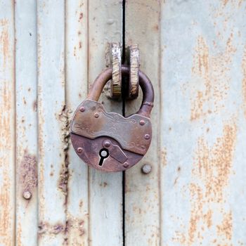 Rusty old padlock on a metal fence