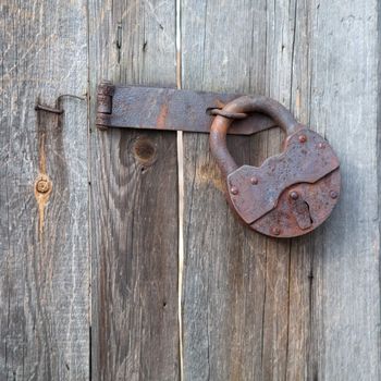 Rusty old padlock on a wooden fence