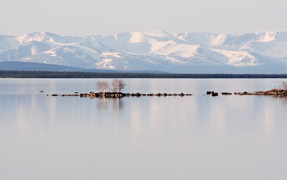 Stony island among lake on a background of mountains