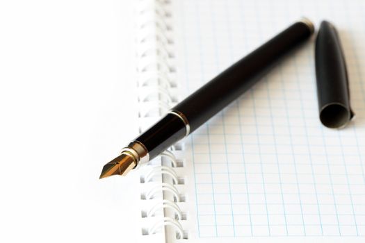 Closeup of fountain pen lying on open spiral notebook