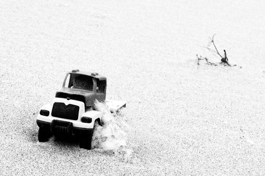 Broken toy car in sand