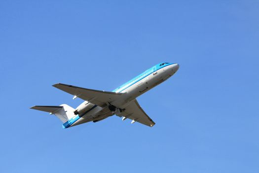 A two engine aircraft departing in a clear blue sky