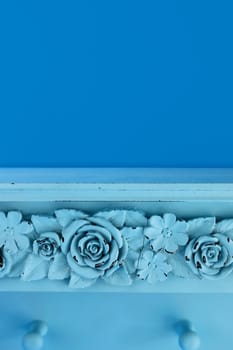 Carved blue rose flower painted wooden shelf. Blue background with copy space