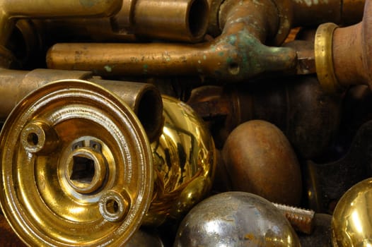 Background comprised of antique brass objects including taps and door knobs.