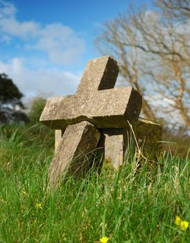 granite cross in overgrown cemetary
