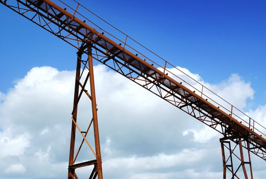 Detail of old mining conveyor belt against blue sky background