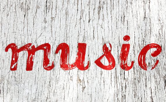 Old chipped white sign with the word "music" written in red paint