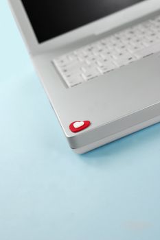 Red & white foam hearts sitting on laptop. Blue background with copy space. Online Love concept