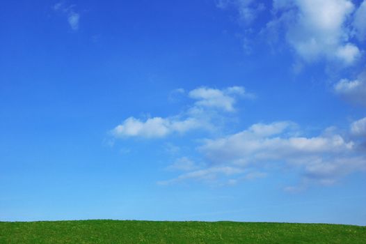 Green hilltop with blue cloudy sky background. Copy Space. Summertime concept