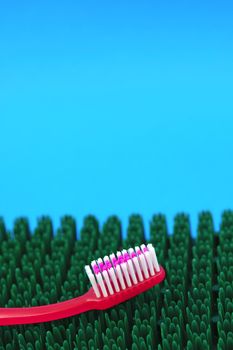 Pink toothbrush on synthetic grass mat. Dental hygiene concept