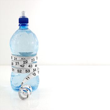 Measuring tape wrapped round water bottle. Copy Space. Health Concept