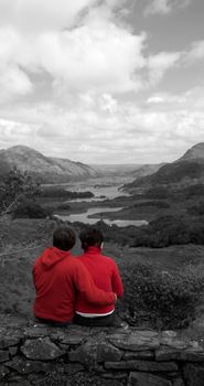 Couple embrassing, view from behind overlooking a stunning landscape.