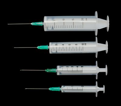 Four white syringes on a black background
