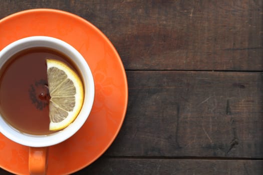 Cup of hot black tea with lemon on wooden background with copy space