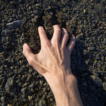 Man's hand clinging stony ground