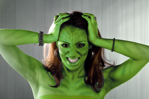 A green alien or Martian woman posing over a silver brushed metal backdrop.