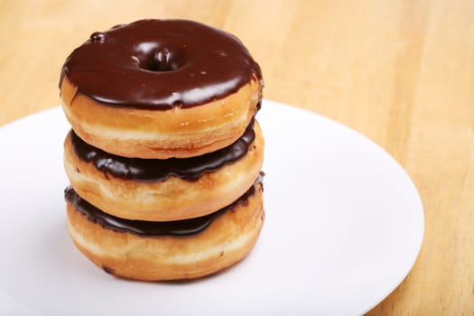 Three chocolate glazed donuts on plate