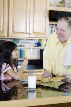 Elderly man sharing cookies with granddaughter