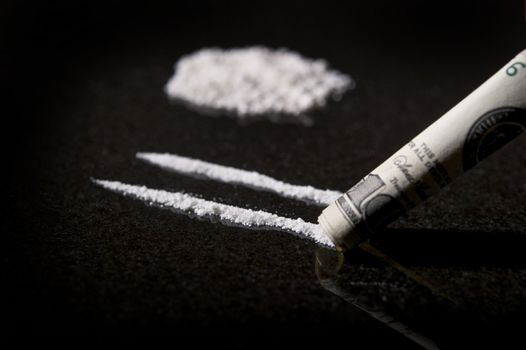 Close up image of lines of cocaine with rolled bill