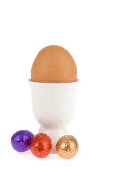 an egg in a egg cup with chocolate eggs