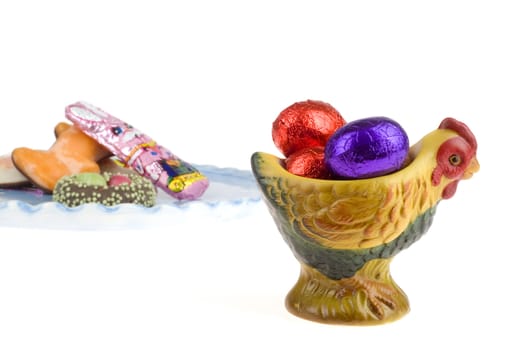 chocolate eggs in a egg cup with a plate on the back with chocolate candies