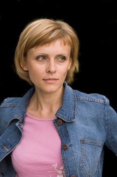 Young cute woman in a denim jacket looking at something (isolated on black)