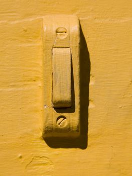 A doorbell on a house wall painted yellow.