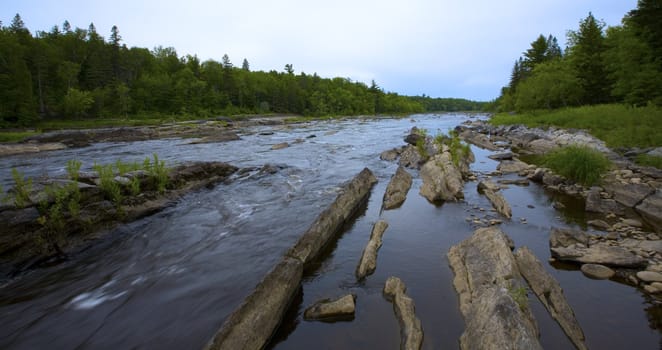 Looking upstream as a river rushes through stone  in the North Woods of Minnesota.