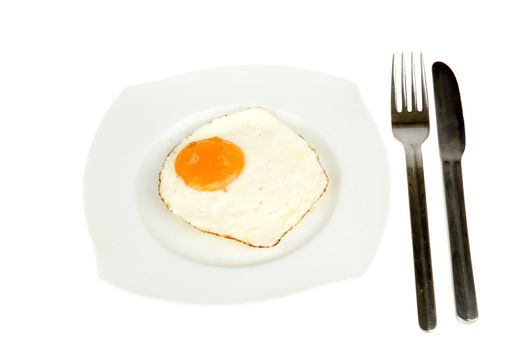 a plate with a fried egg, a fork and a knife