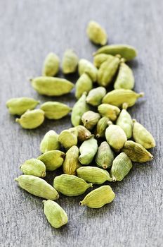 Several whole green cardamom seed pods on wooden background